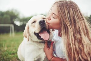 Young woman kissing her labrador - standret iStock
